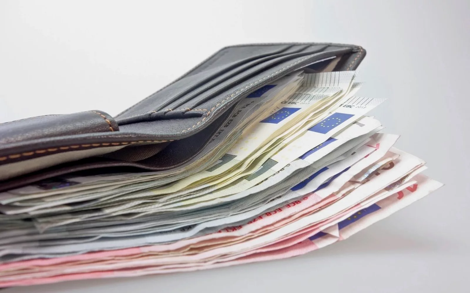 Portfel z wachlarzem banknotów na jasnym tle