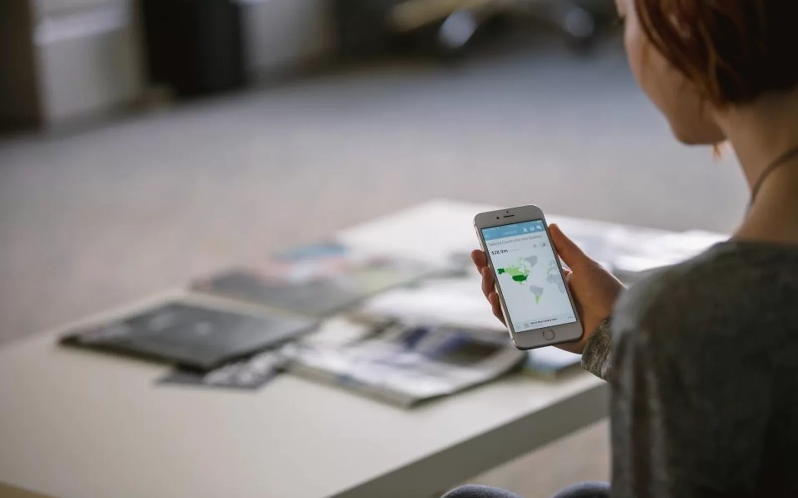Telefon z otwartą aplikacją i dokumenty na biurku obok laptopa