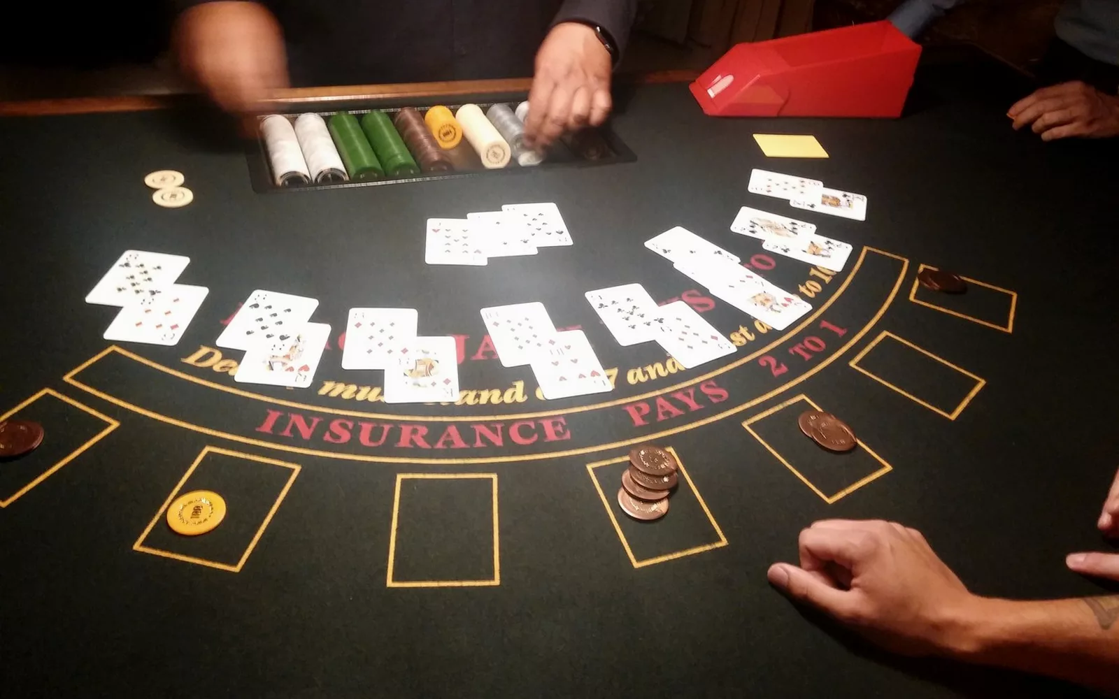 Stół do blackjacka z rozłożonymi kartami i rękami krupiera